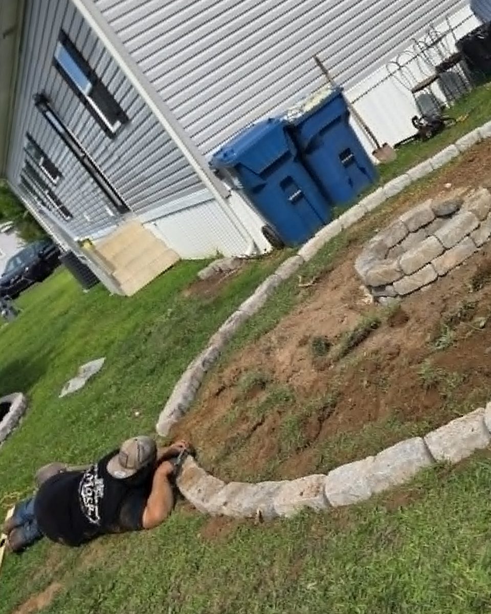 Granite block border course being set to hold the edge of a round gravel patio