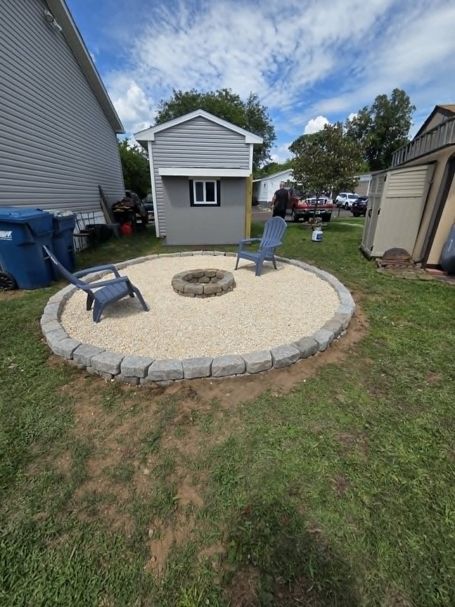 Finished round gravel sitting area with a stone fire pit at the center and Adirondack chairs on the gravel