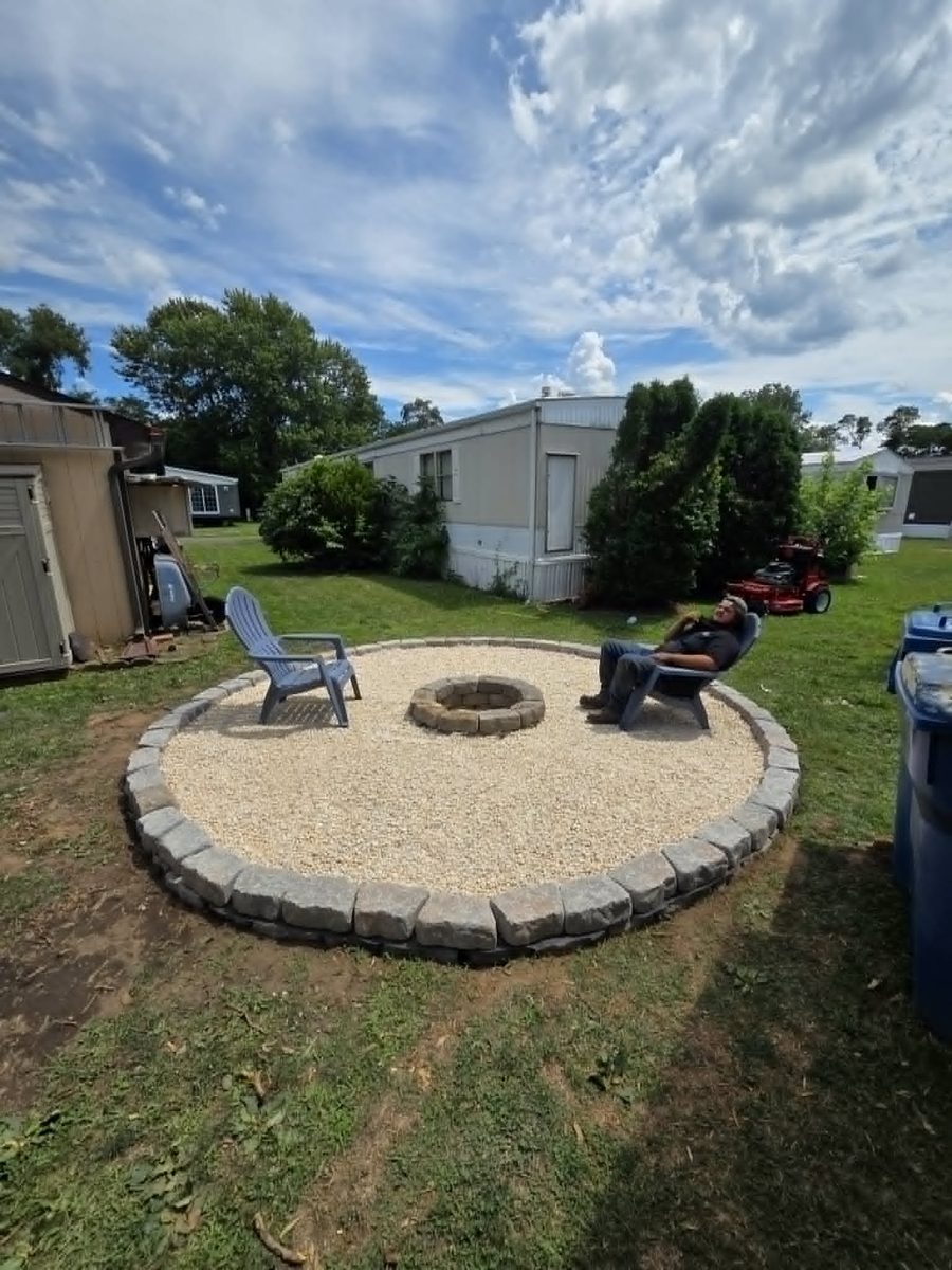 Finished fire pit sitting area seen from across the back yard with the block border set flush to the lawn