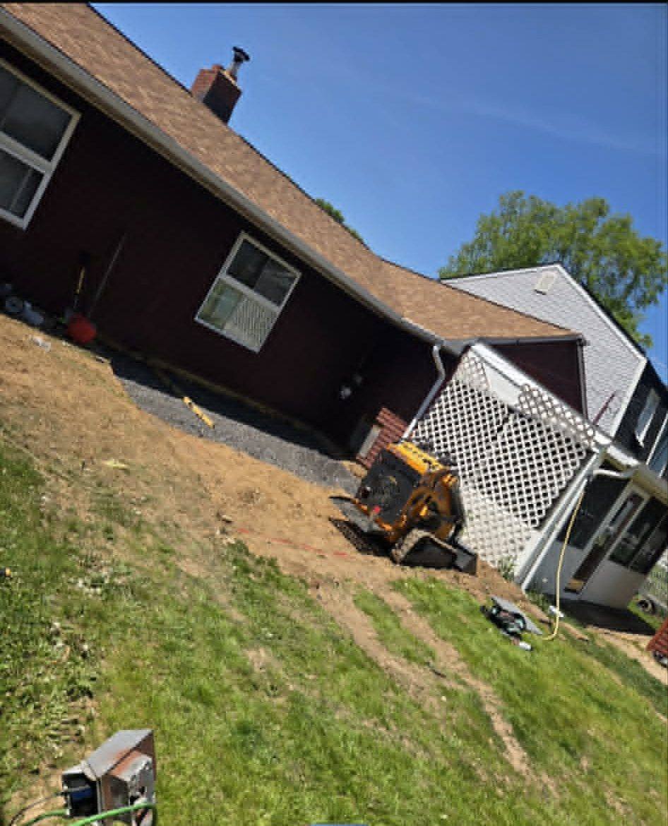 Track loader placing compacted stone base for a paver patio behind a Bucks County home