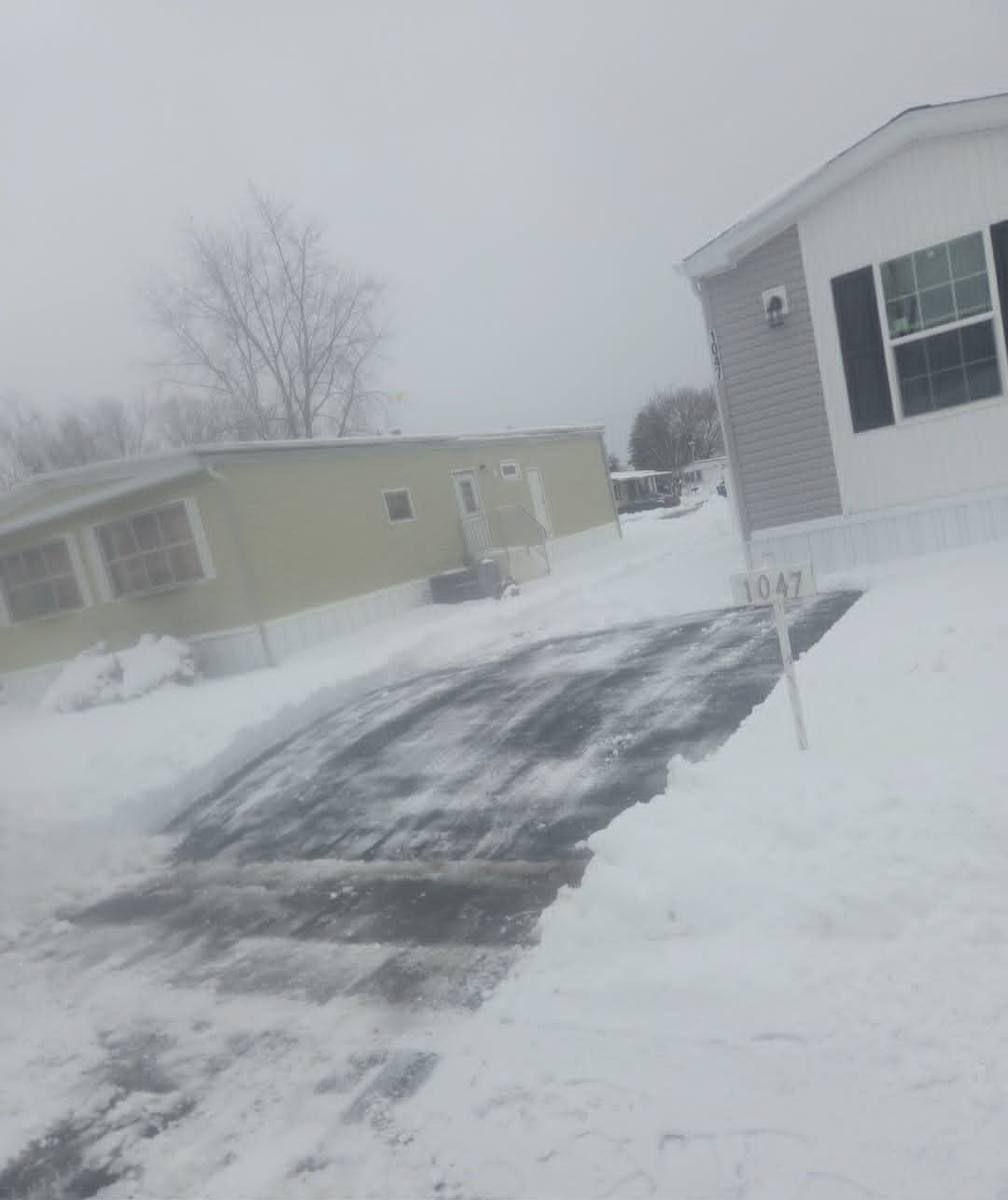 Driveway cleared to the pavement with snow stacked clear of the mailbox during an active storm